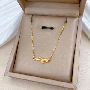 Detailed view of a gold bow pendant necklace resting in a premium jewelry display box