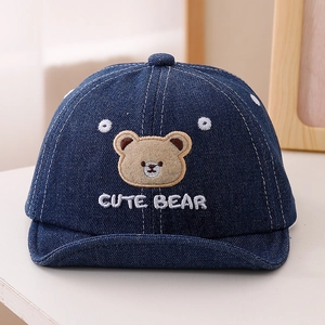 Détail de la broderie ours sur le tissu en jean bleu foncé de la casquette pour enfants