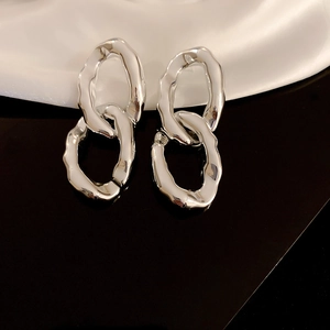 Détail de boucles d'oreilles argentées à double boucle avec texture métallique polie