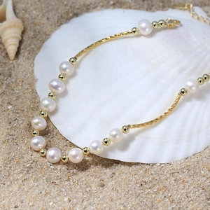 Elegant s925 silver and freshwater pearl bracelet with gold tubes on a white seashell