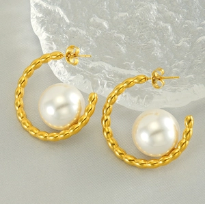 Macro detail of gold-plated ripple hoop earrings with large white pearl drop