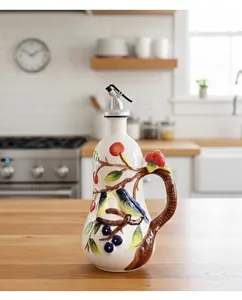 Detail of hand-painted ceramic oil dispenser with bird and berry motifs and a steel spout