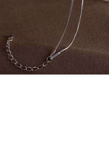 Close-up of silver snake chain and extension clasp on a minimalist steel bracelet