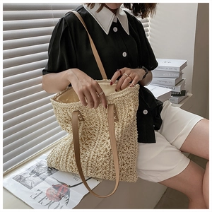 Detail of woven cutout pattern and brown leather straps on a cream shoulder tote bag