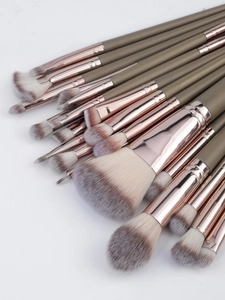 Close-up of olive green makeup brushes with rose gold ferrules and soft fiber bristles