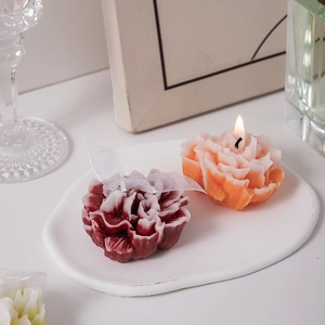 Detailed view of red and orange carnation candles on a ceramic tray for home decor