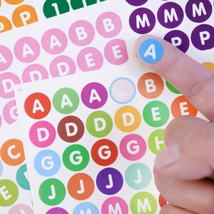 Close-up of peeling a blue letter A from a colorful 0.5 inch waterproof alphabet sticker sheet