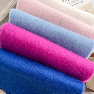Gros plan d'écharpes moelleuses en mohair bleu, rose et crème avec de longues franges