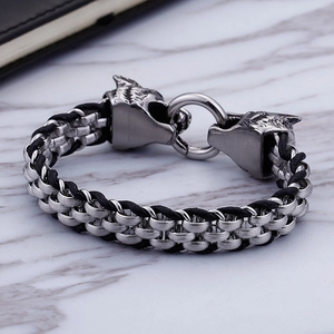 Close-up of dual wolf head connectors and braided leather cord on a vintage steel bracelet