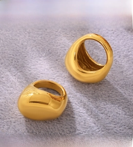 Detailed macro view of two PVD electroplated 18K gold chunky dome rings on fabric
