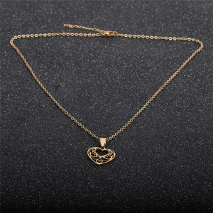 Polished gold titanium steel hollow heart pendant necklace on a dark textured background