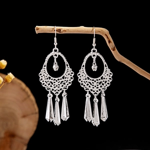 Detail shot of silver hollow mesh earrings with bells and prism tassels on wood