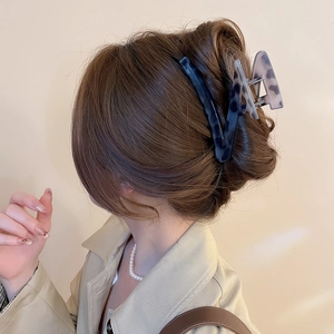 Detail view of a tortoiseshell V-shaped hair claw clip worn on a low bun by a model