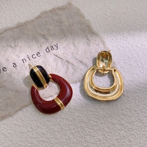 Detail of vintage red and black enamel gold plated earrings on a textured background