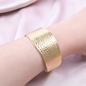 Polished gold C-shape wide cuff bracelet with hammered texture on pink silk