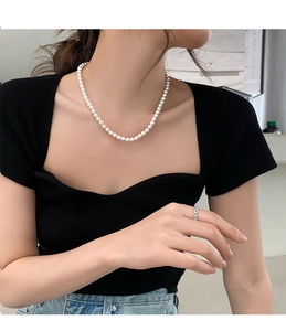Gros plan d'un collier de perles blanches élégant et d'une bague en argent sur un mannequin