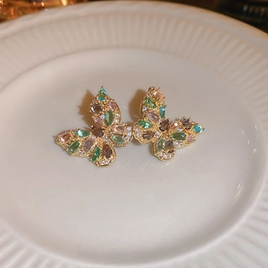 Close-up of golden butterfly earrings with colorful gemstones and sparkling crystal accents