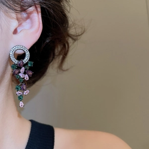 Close-up of vintage style drop earrings featuring purple and green zircon gemstones