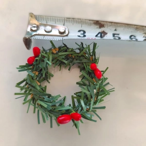 Close-up of mini artificial Christmas wreath with pine needles and red berries for decoration