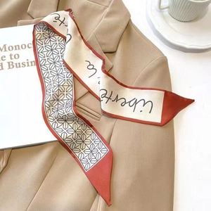 Close-up of a satin twilly scarf with geometric patterns on a khaki blazer collar