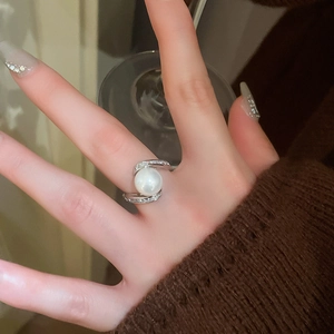 Gros plan d'une bague perle argentée avec anneau torsadé serti de zircons au doigt