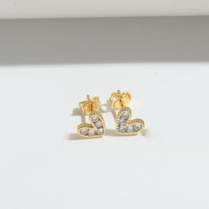 Macro detail of heart stud earrings featuring gold plating and micro-paved white zircons