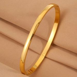 Macro shot of gold-plated hinged bangle on silk fabric with polished mirror finish