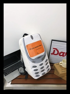 Detail view of retro mobile phone shaped backpack in white PU leather on wooden bench