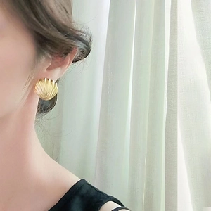 Elegant gold shell-shaped earrings for women shown on model in natural light