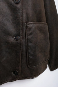 Detail of dark brown faux leather jacket with resin buttons and textured stitching