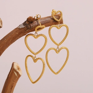Golden multi-layer heart drop earrings with twisted rope texture on a dry branch