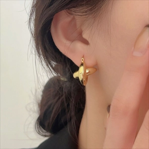 Detailed view of high-shine gold multi-dimensional cross earrings on a model