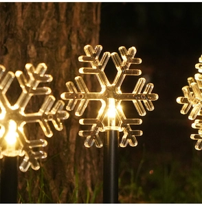Detail of snowflake-shaped outdoor solar stake light with warm yellow LED illumination