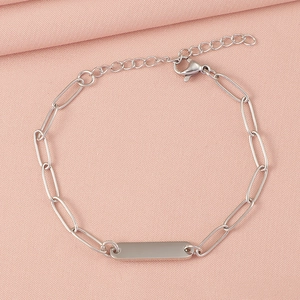 Close-up of a silver paperclip chain bracelet with a polished engravable bar on pink fabric