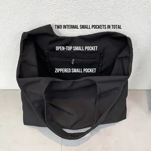 Grand sac cabas noir en toile montrant l'intérieur spacieux avec poches zippées et ouvertes