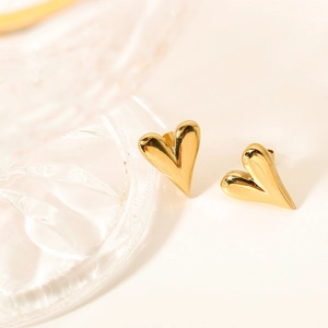 Detailed view of polished heart-shaped gold studs placed on a clear glass prop