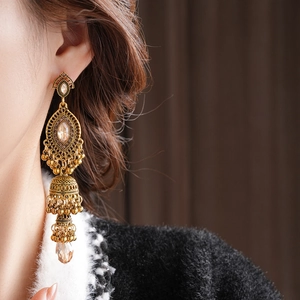 Macro de boucles d'oreilles Jhumka vintage dorées avec franges et strass bruns sur mannequin