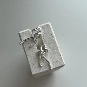 Elegant 925 sterling silver bow stud earrings with zircon crystals on a white stone base