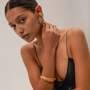 Detail of 18k gold plated stainless steel flower earrings with hammered lava texture