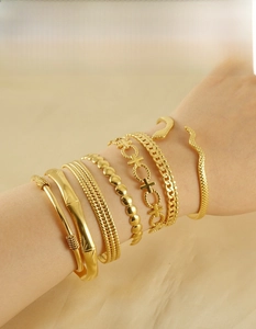 Close-up of six gold-plated C-shaped stainless steel bangles styled on a woman's wrist
