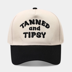 Two-tone baseball cap with TANNED and TIPSY 3D embroidery on a minimalist background