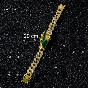 Dettaglio macro di un bracciale hip-hop dorato da 20 cm con un ciondolo verde San Giuda