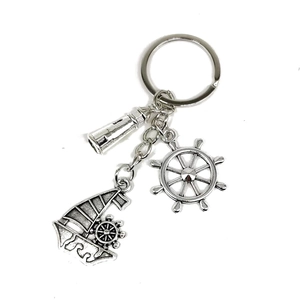 Vintage nautical keychain with silver sailboat, lighthouse, and anchor charms on white background
