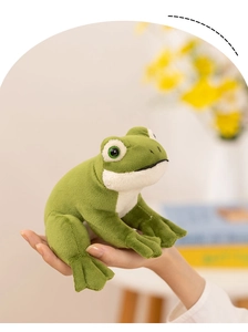 Close-up of a small green plush frog toy held in hand featuring soft texture and realistic eyes