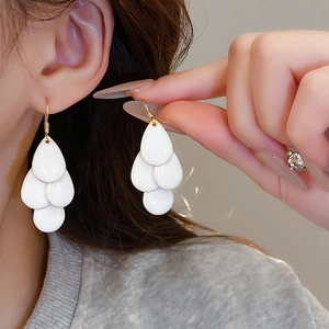 Close-up of elegant tiered white teardrop tassel earrings with polished enamel finish