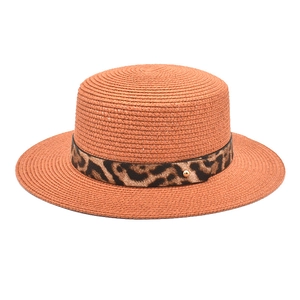 Dettaglio cappello di paglia arancione con nastro leopardato e perla dorata