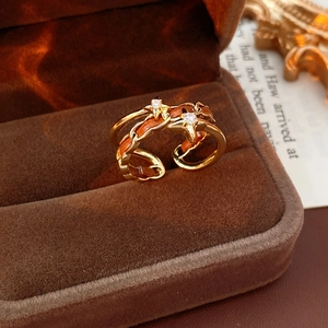 Détail macro d'une bague étoile vintage avec finition dorée et cuir tressé orange