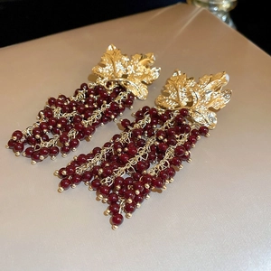 Detail of vintage gold leaf earrings with dark red bead tassel grape-like clusters