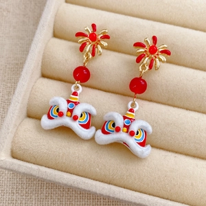 Detailed close-up of festive enamel lion dance earrings with red pearls in a jewelry box