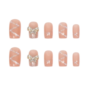 Detailed view of nude pink press-on nails with 3D rhinestone bows and pearls